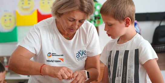 Eine Helferin der Organisation Ave Copiii arbeitet mit einem Kind gemeinsam an einem Bastelprojekt