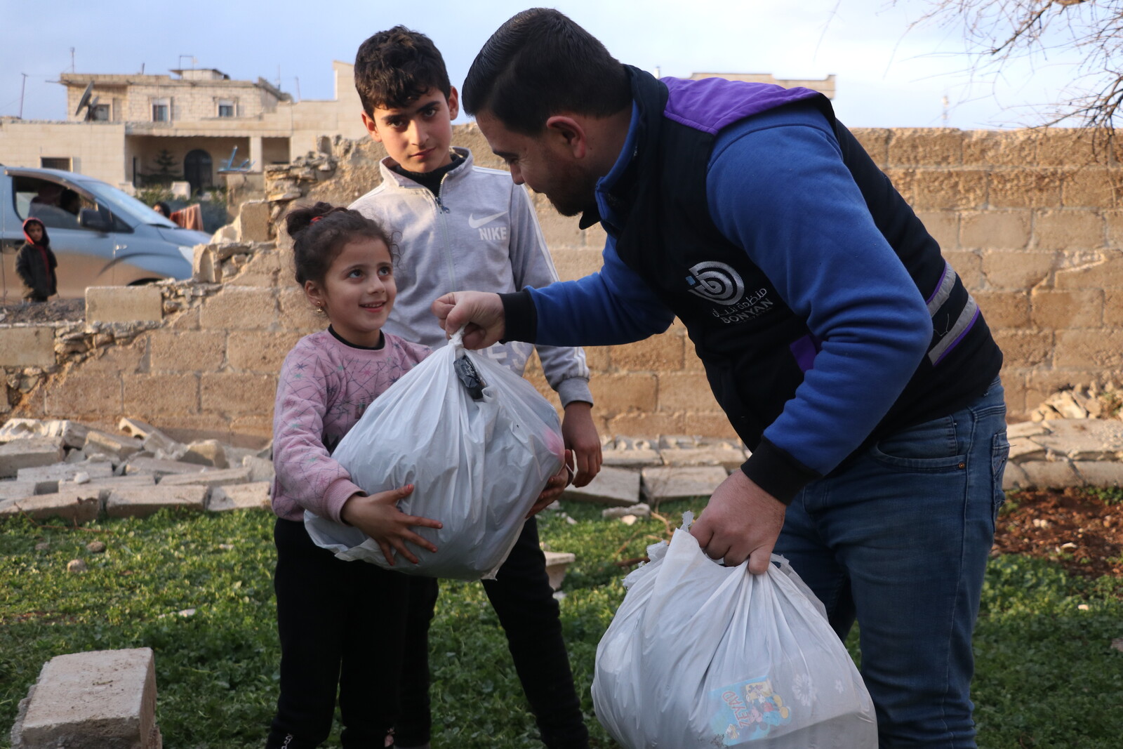 Ein Helfer von arche noVa verteilt Hilfsgüter an Kinder in Syrien