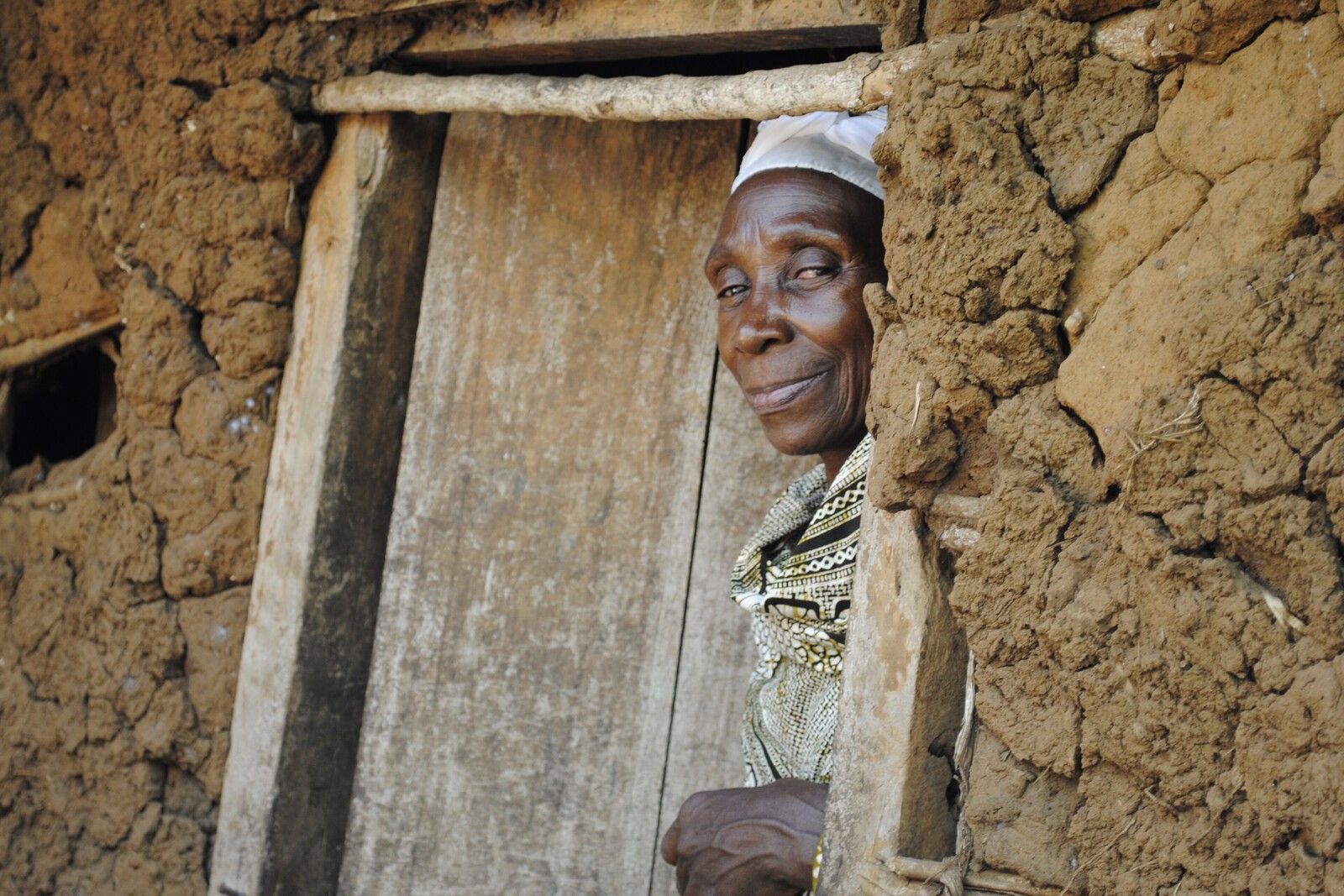 An old woman is poking out of a door frame