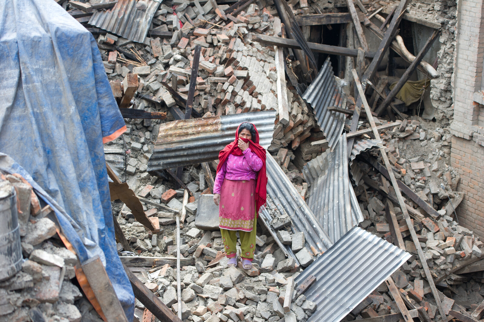 Eine Frau steht in den Trümmern, die einmal ihr Haus waren. In Nepal verwüstet ein schweres Beben innerhalb von Sekunden ganze Städte und Dörfer.