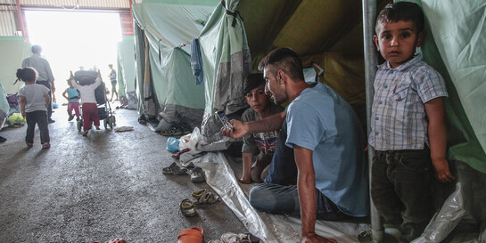 Eine syrische Flüchtlingsfamilie sitzt vor ihrem Zelt