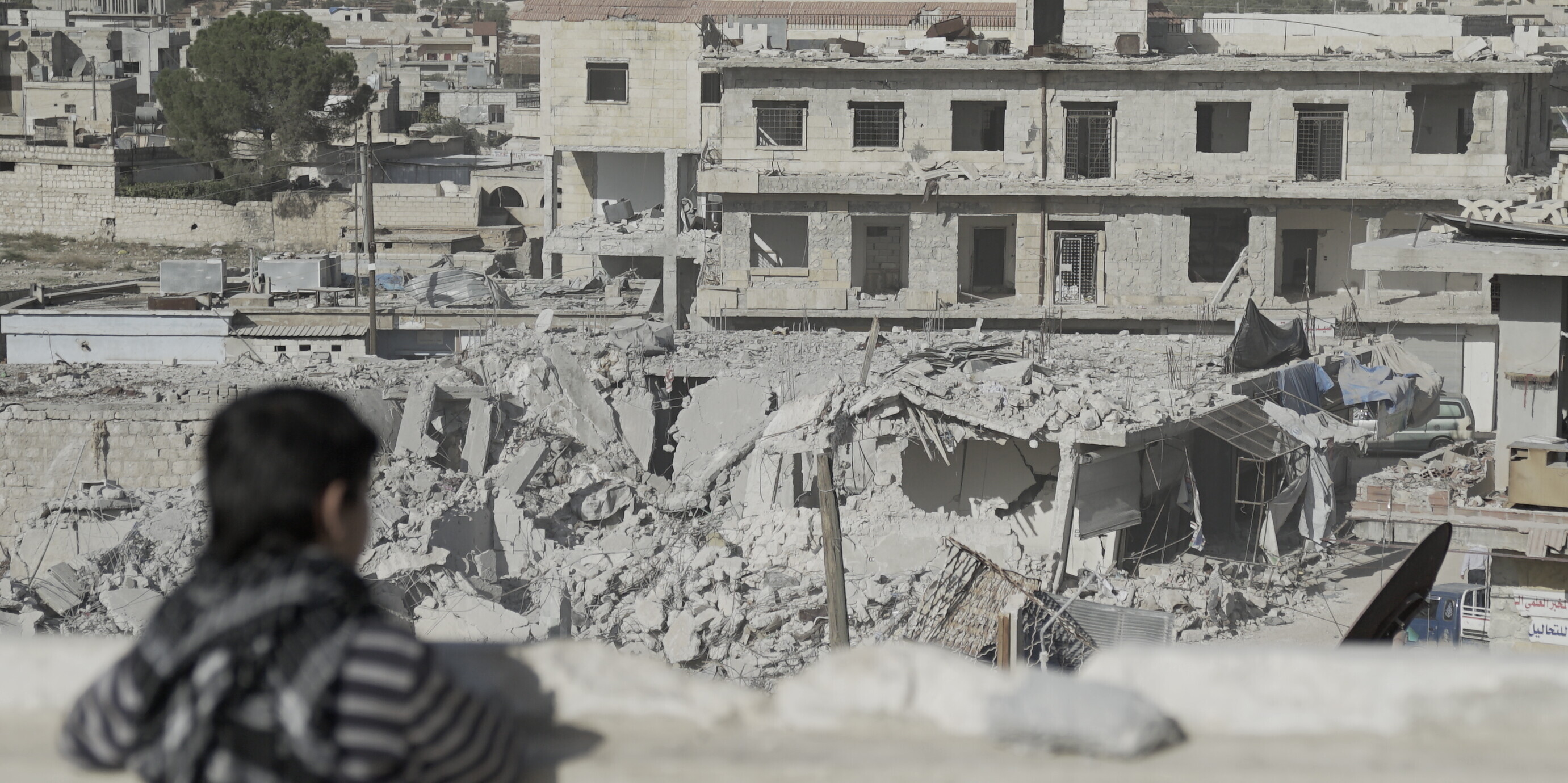 Ein Kind in Syrien blickt auf eine von Bomben zerstörte Stadt