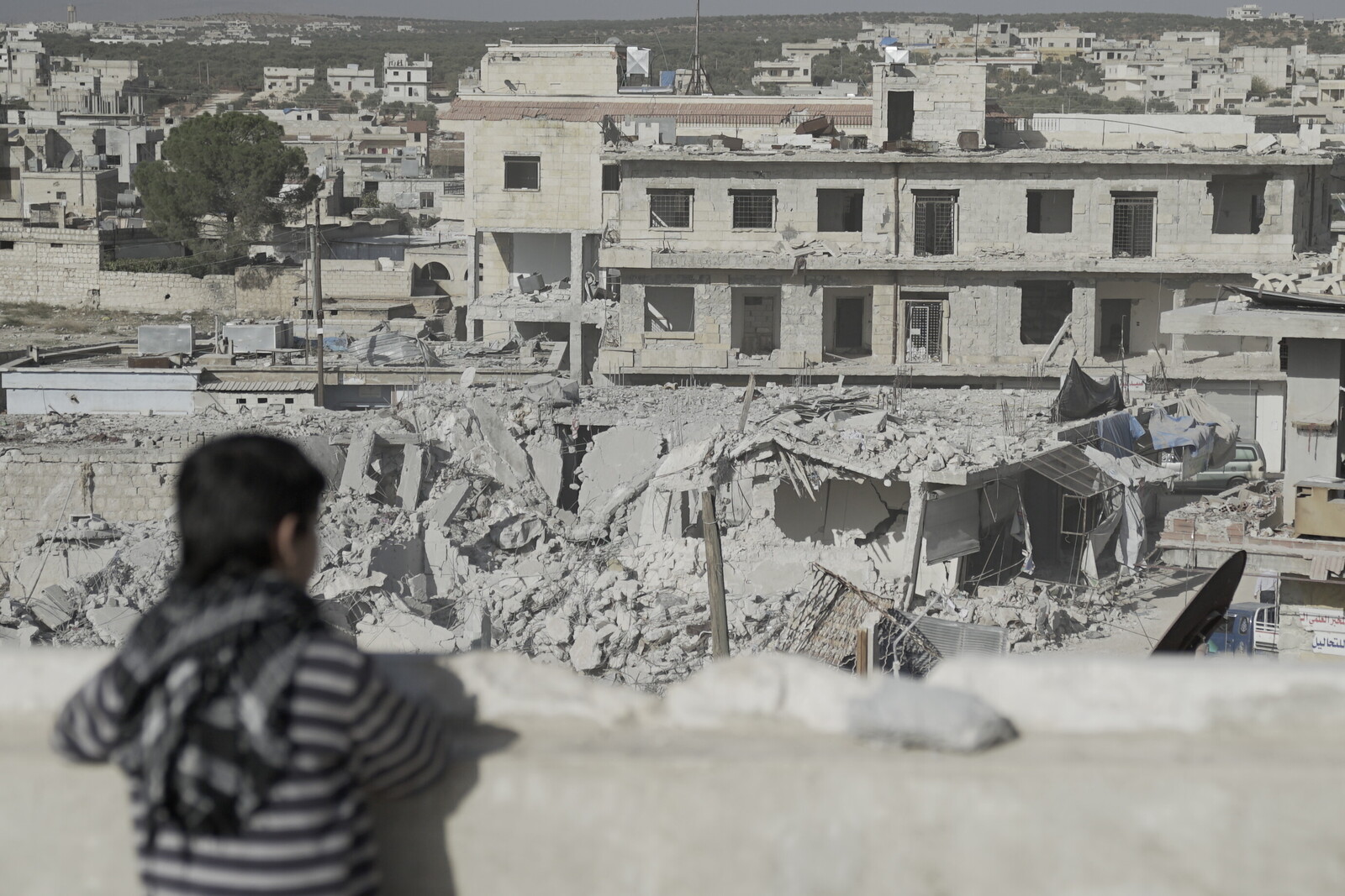 Ein Kind in Syrien blickt auf eine von Bomben zerstörte Stadt