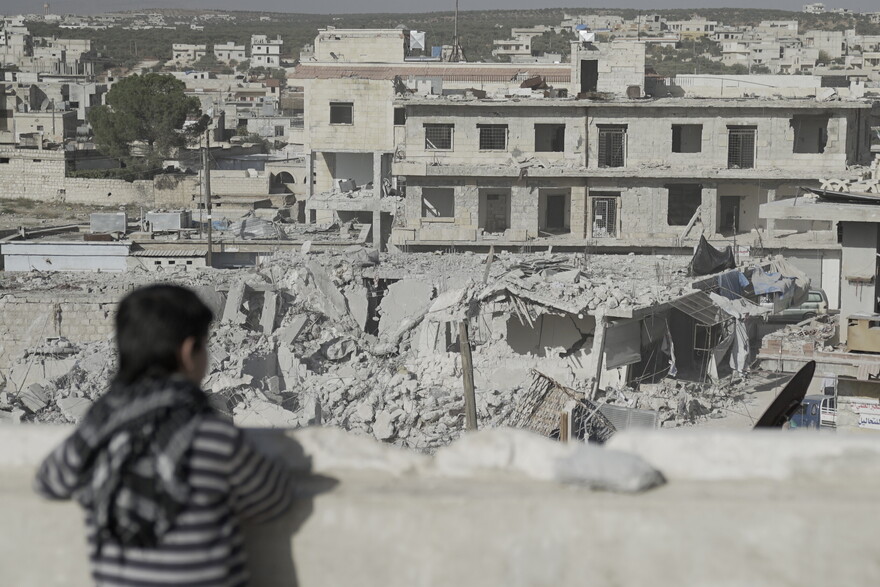 Ein Kind in Syrien blickt auf eine von Bomben zerstörte Stadt