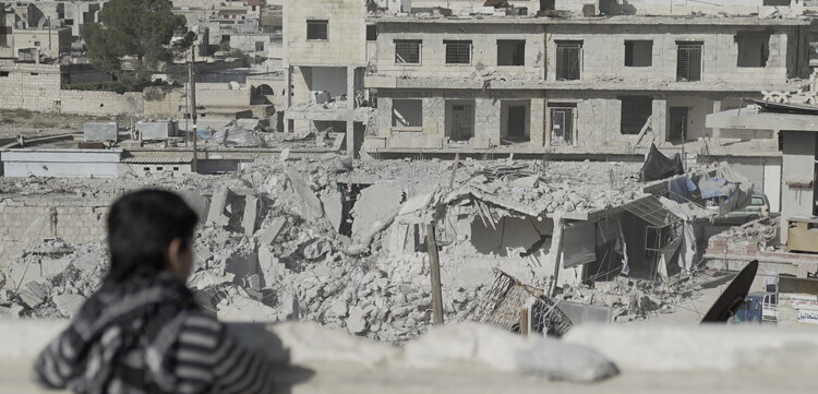 Ein Kind in Syrien blickt auf eine von Bomben zerstörte Stadt