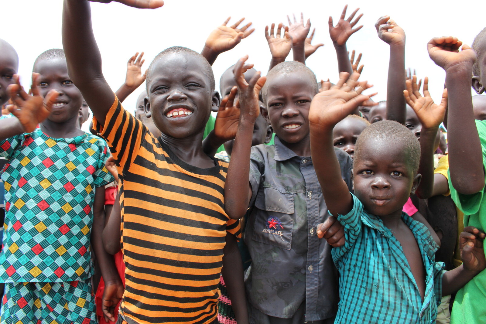 Aus dem Südsudan geflüchtete, winkende Kinder in einem Flüchtlingscamp in Uganda 