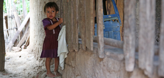 In Guatemala steht ein Kind vor einem zerstörten Haus.