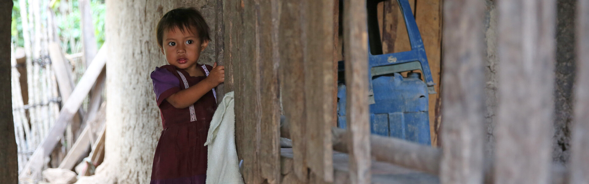 In Guatemala steht ein Kind vor einem zerstörten Haus.