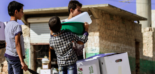 In Syrien packen Kinder Kartons auf eine Schubkarre