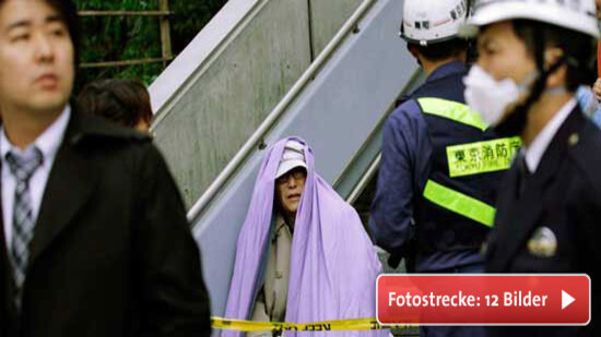 Im Finanzdistrikt Tokios sitzt ein Mann nach seiner Evakuierung in Decken gehüllt auf einer Treppe. © REUTERS/KYODO Kyodo