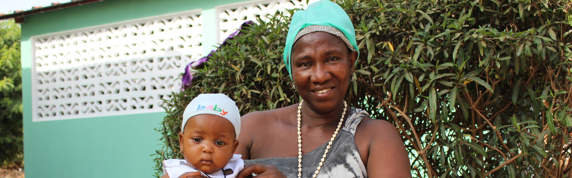 A baby girl sits in the lap of a woman in Guinea-Bissau