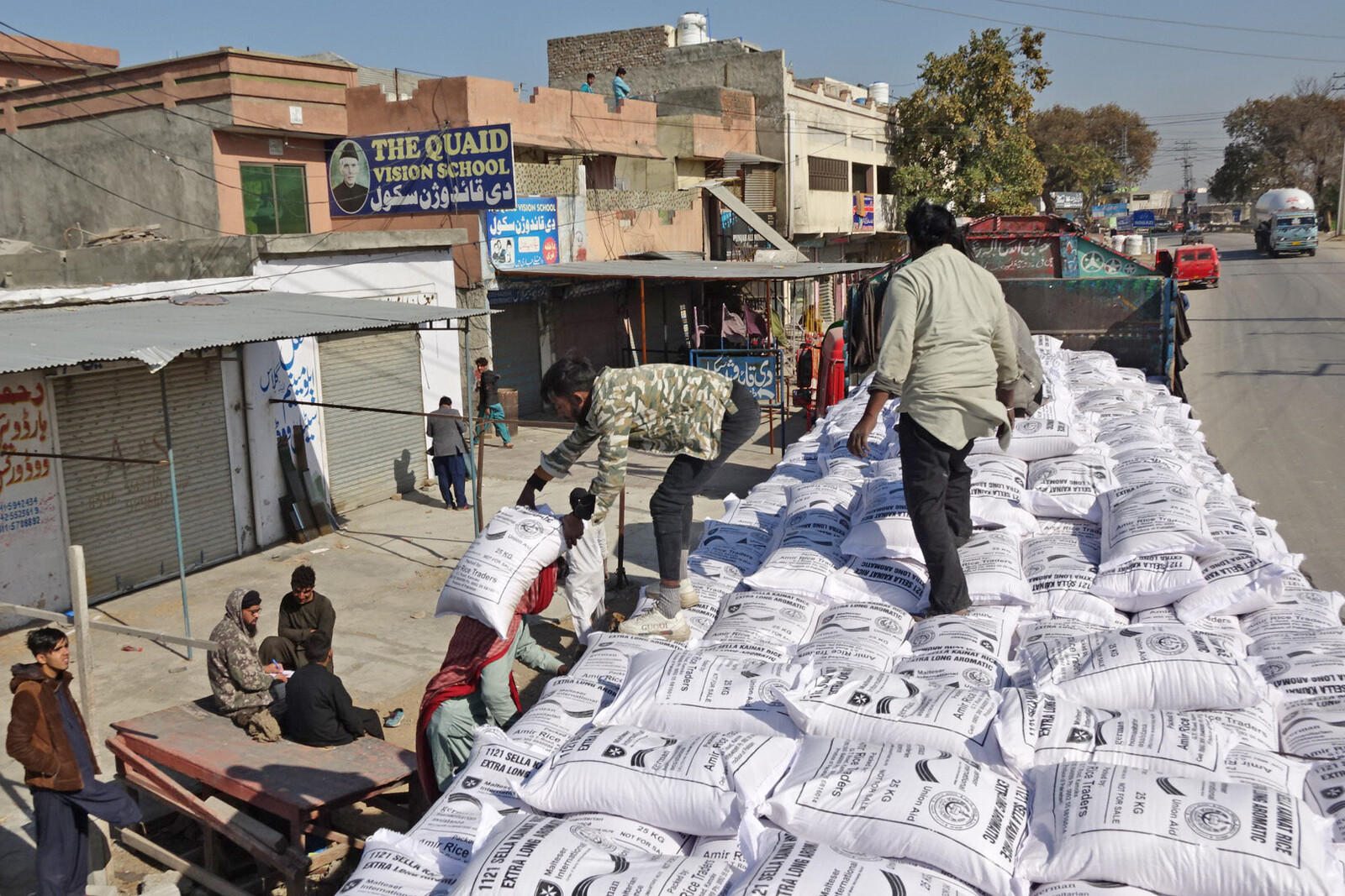 Helfer der Organisation Malteser International verteilen an die afghanische Bevölkerung Reissäcke von einem Lastwagen aus