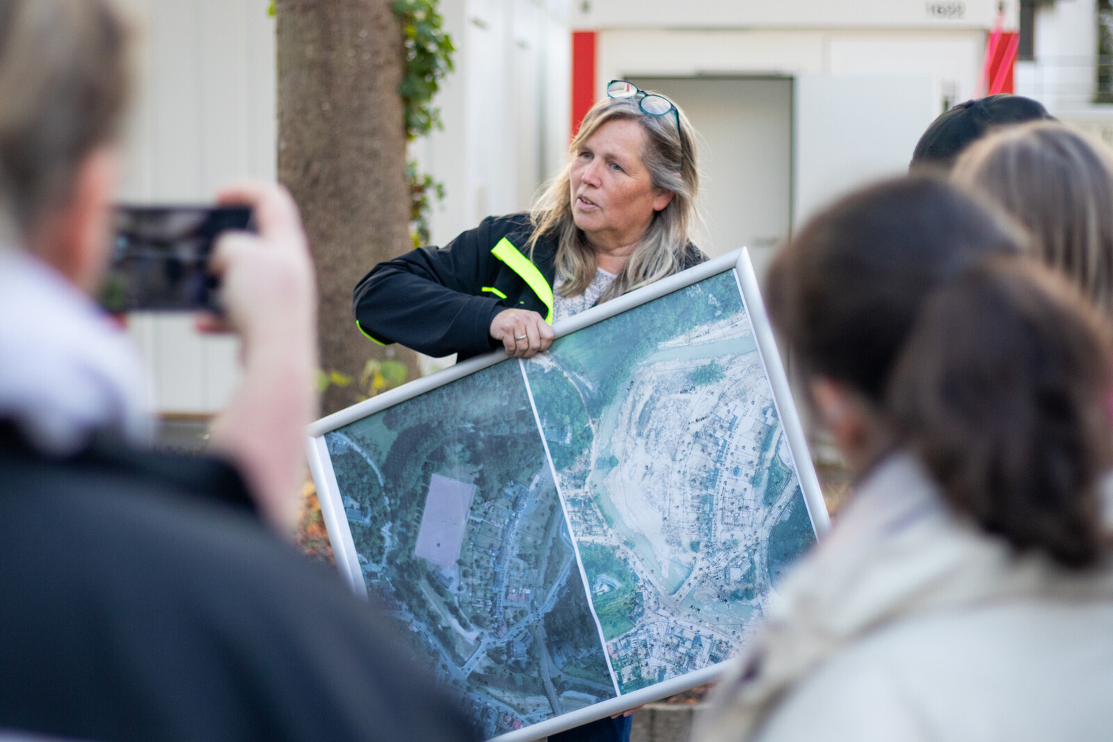 Eine Frau zeigt auf einer Karte das Hochwassergebiet vor und nach der Katastrophe