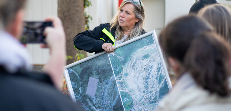 Eine Frau zeigt auf einer Karte das Hochwassergebiet vor und nach der Katastrophe