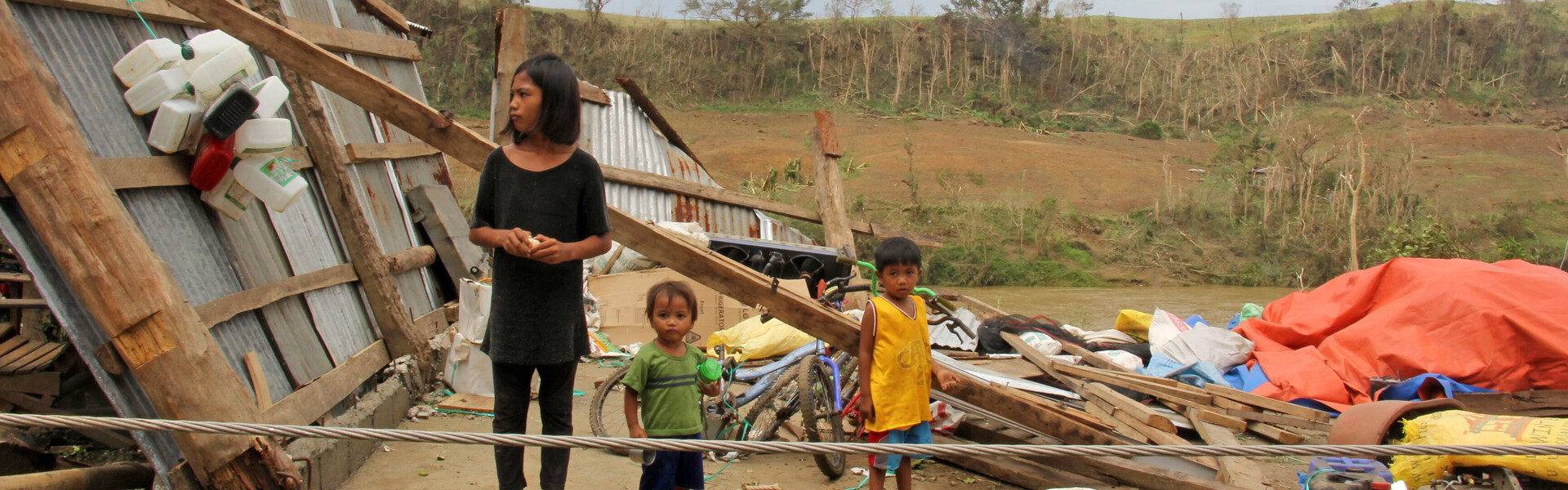 Frau & Kinder inmitten der Zerstörung, die Taifun Mangkhut im Norden der Philippinen hinterließ