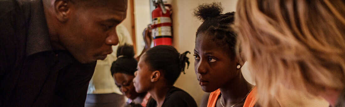 Helferin und zwei Haitianer in einer Notunterkunft