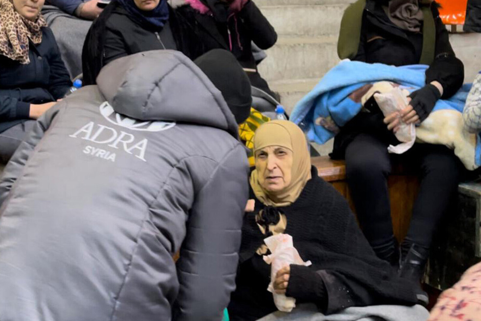 Helferin von ADRA im Gespräch mit Menschen in einer Notunterkunft nach dem Erdbeben in Syrien