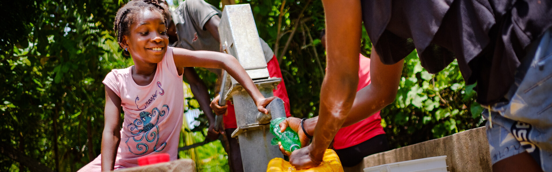 Ein Mädchen in Haiti freut sich über das fließende Wasser.