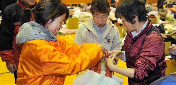 Lachend überreicht die Mitarbeiterin von World Vision die Taschen mit den Hygiene-Kits.