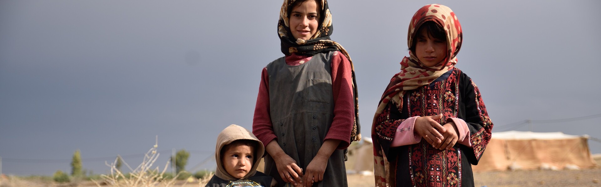 In Syrien stehen drei Flüchtlingskinder. Sie sind Betroeffene der Flüchtlingskrise in Syrien