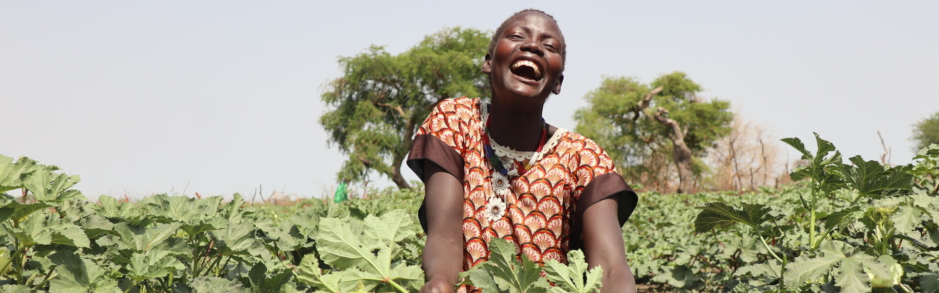 Junge lächelnde Landwirtin auf einem Feld in Afrika