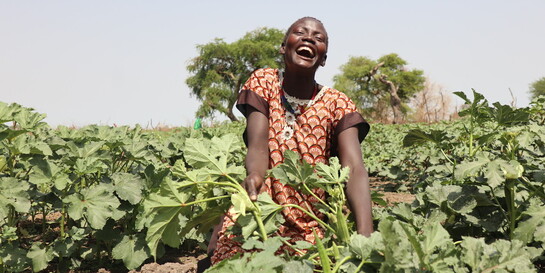 Junge lächelnde Landwirtin auf einem Feld in Afrika