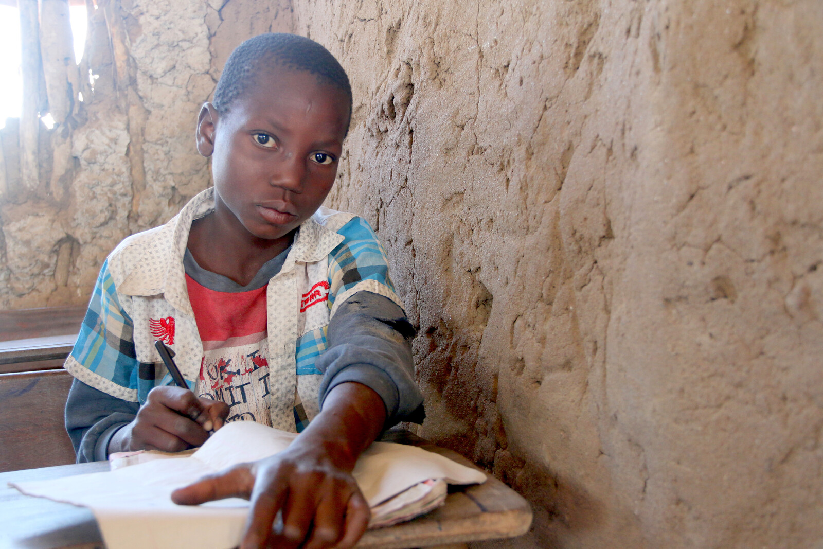 Ein Junge in Mosambik schreibt in ein Buch in der Schule während der Dürrekatastrophe in El Niño