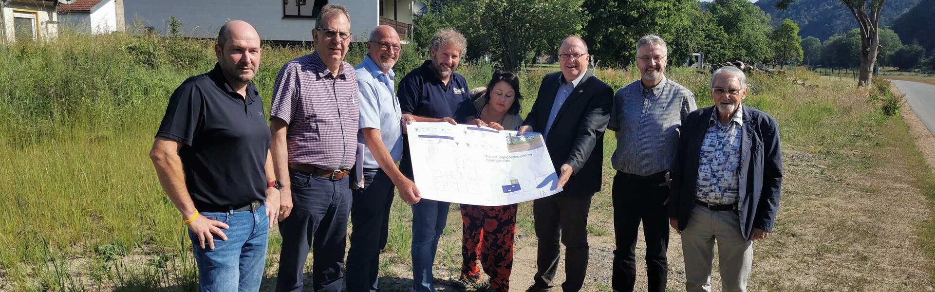 action medeor und Vertreter der Gemeinde Hönningen-Liers halten den Bauplan der neuen Tagespflege-Einrichtung in der Hand