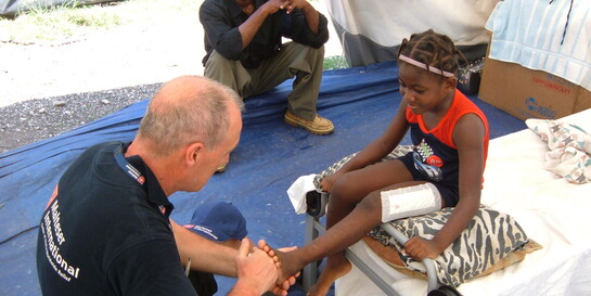 Ein Helfer von den Maltesern versorgt das Bein eines Mädchens nach dem Erdbeben in Haiti  