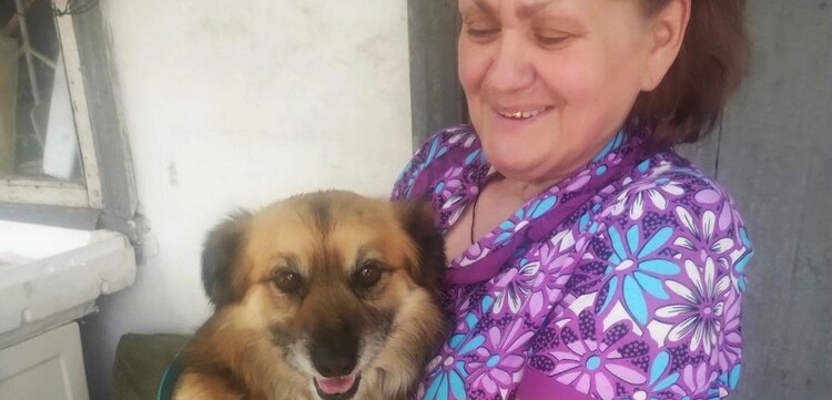 Eine ältere Frau mit einem Hund auf dem Arm