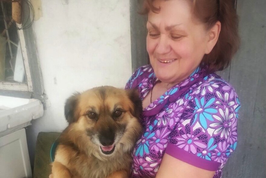 Eine ältere Frau mit einem Hund auf dem Arm