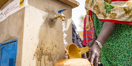 In Mali füllt eine Frau Wasser in einen Behälter (Symbolbild)