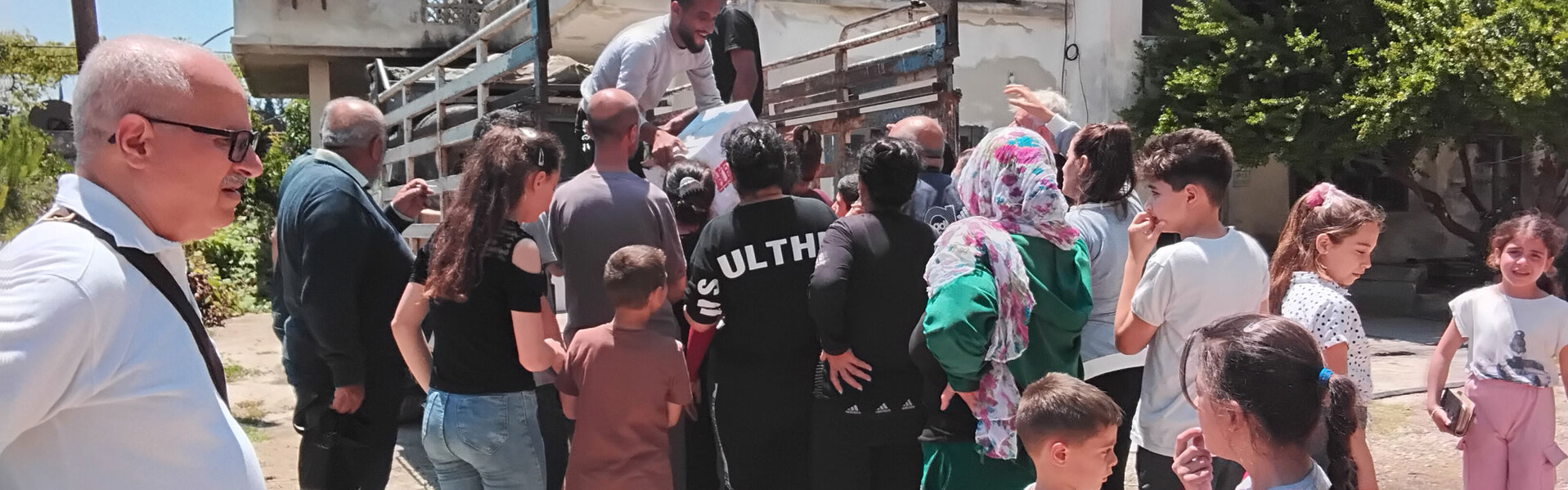 Helfer verteilen Hilfsgüter in Syrien von einem Lastwagen an eine Menschenmenge Helfer verteilen Hilfsgüter in Syrien von einem Lastwagen an eine Menschenmenge