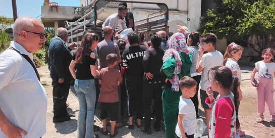 Der Helfer Dr. Ali Al-Zakami übergibt einer Frau in Syrien ein Lebensmittelpaket
