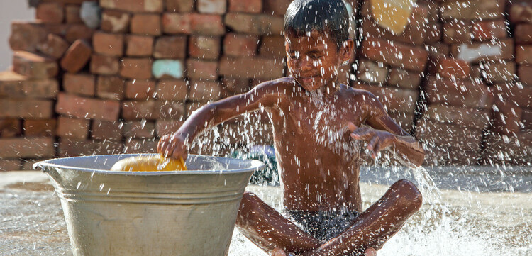 Ein Junge spielt mit Wasser.