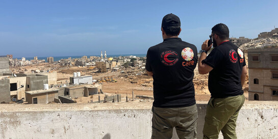 Zwei Helfer besprechen sich zur Lage nach der Flut in Libyen