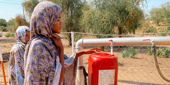 Zwei Frauen im sudanesischen Abu Hashim füllen Wasser in einen roten Kanister ab