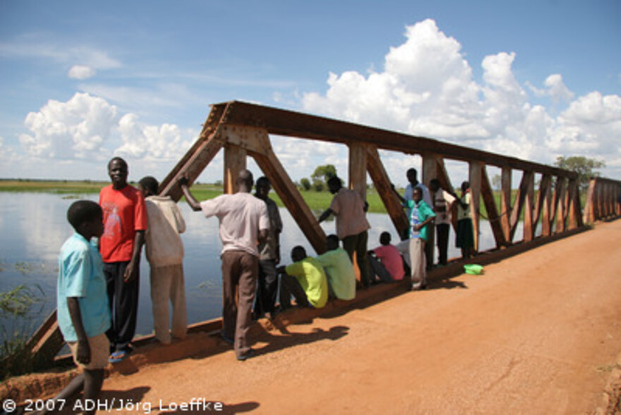 Flut Afrika: Menschen beobachten den Wasserstand an einer Brücke