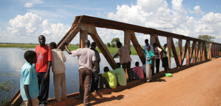 Flut Afrika: Menschen beobachten den Wasserstand an einer Brücke