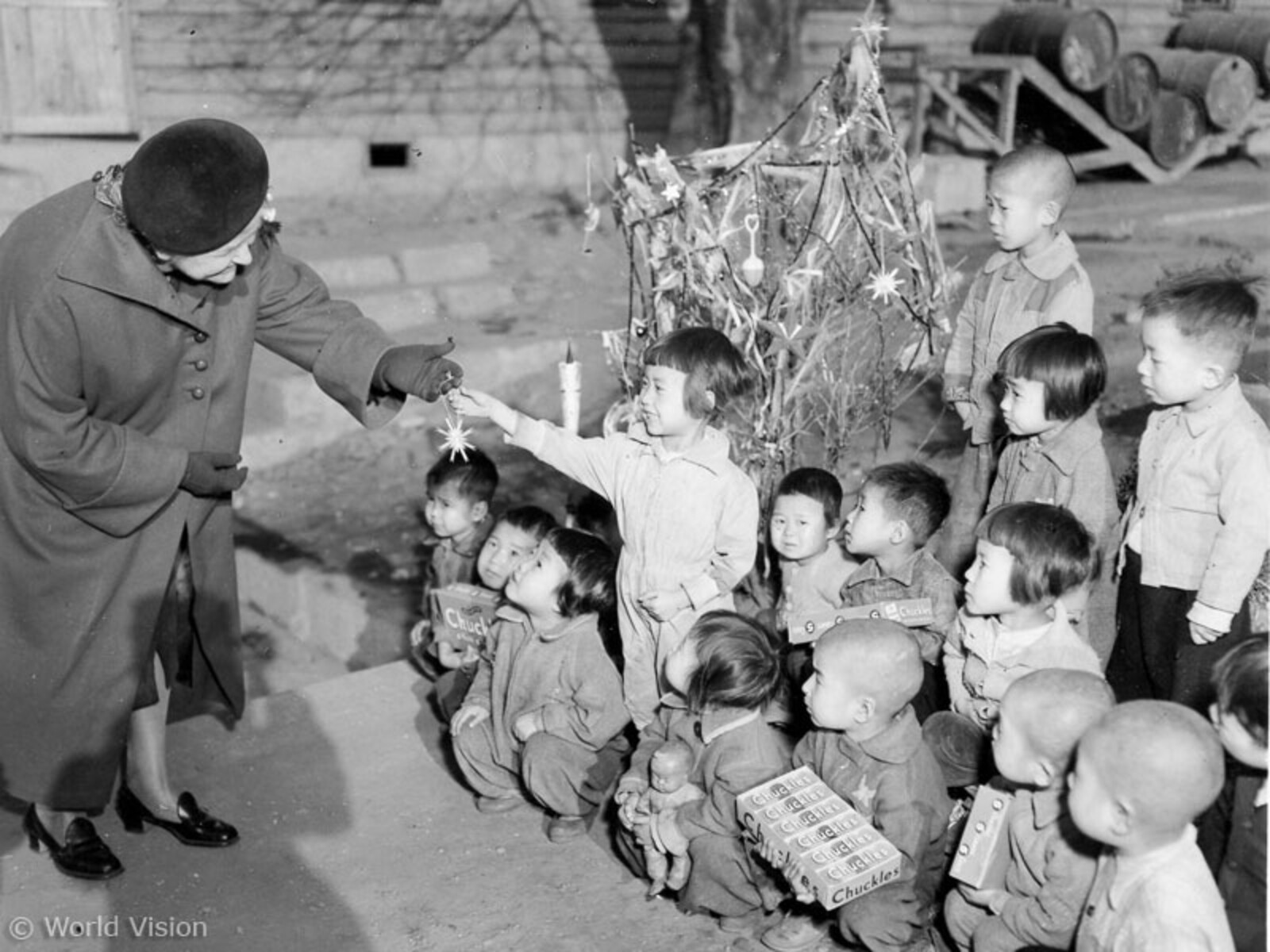 Eine alte Frau schenkt einer Gruppe asiatischer Kinder einen Weihnachtsstern