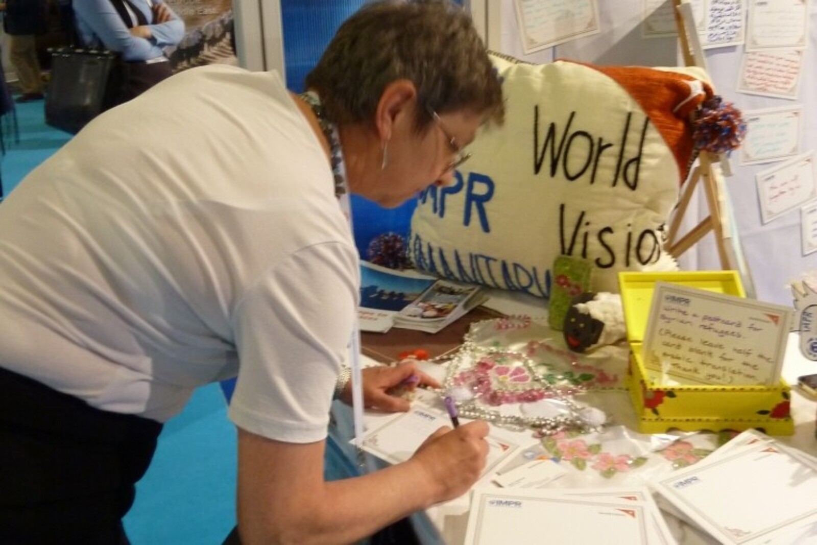 Manuela Roßbach schreibt eine Botschaft auf eine Tafel für Flüchtlinge bei einem World Vision Stand auf dem World Humanitarian Summit.