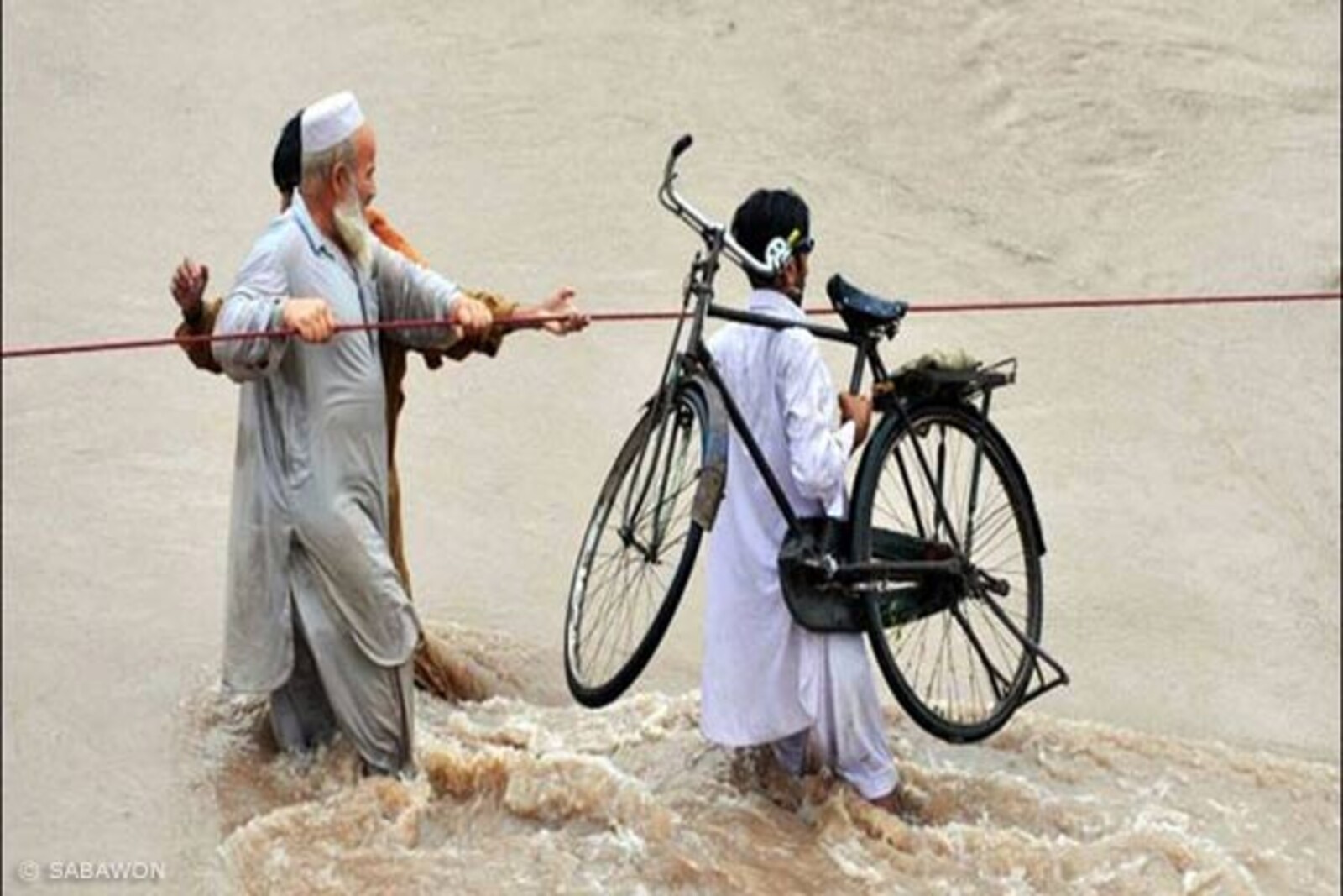 Flut Pakistan: Männer und ein Fahrrad im District DI Khan