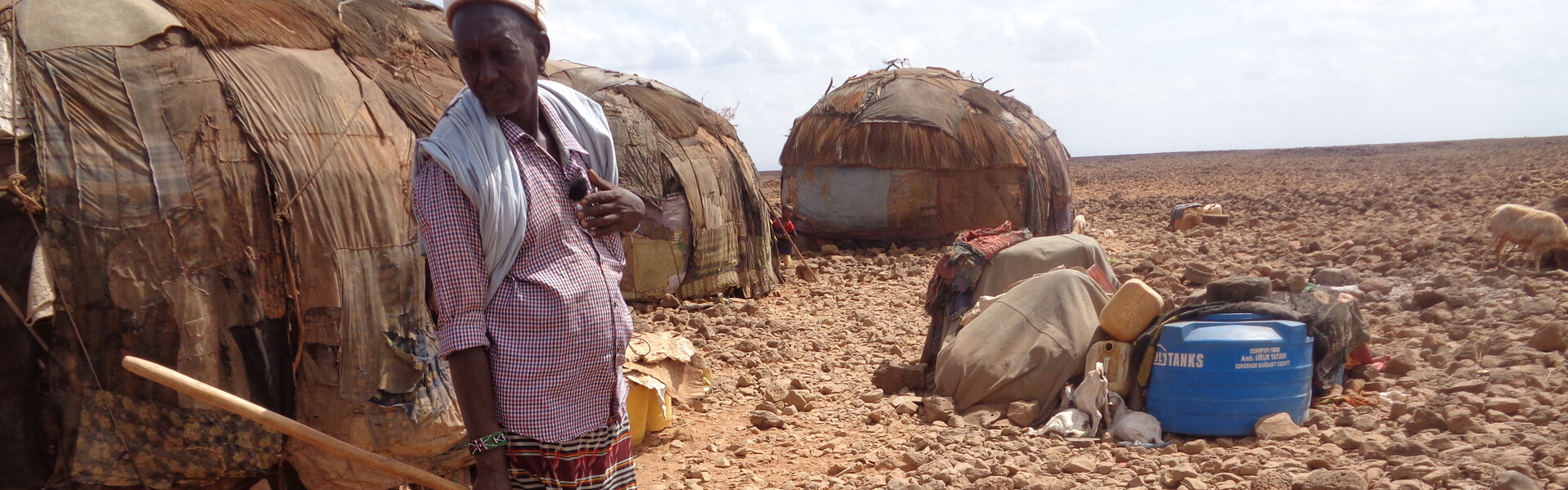 Ein Mann steht in Kenia in der Dürre Afrikas. Im Vordergrund liegt eine tote Ziege
