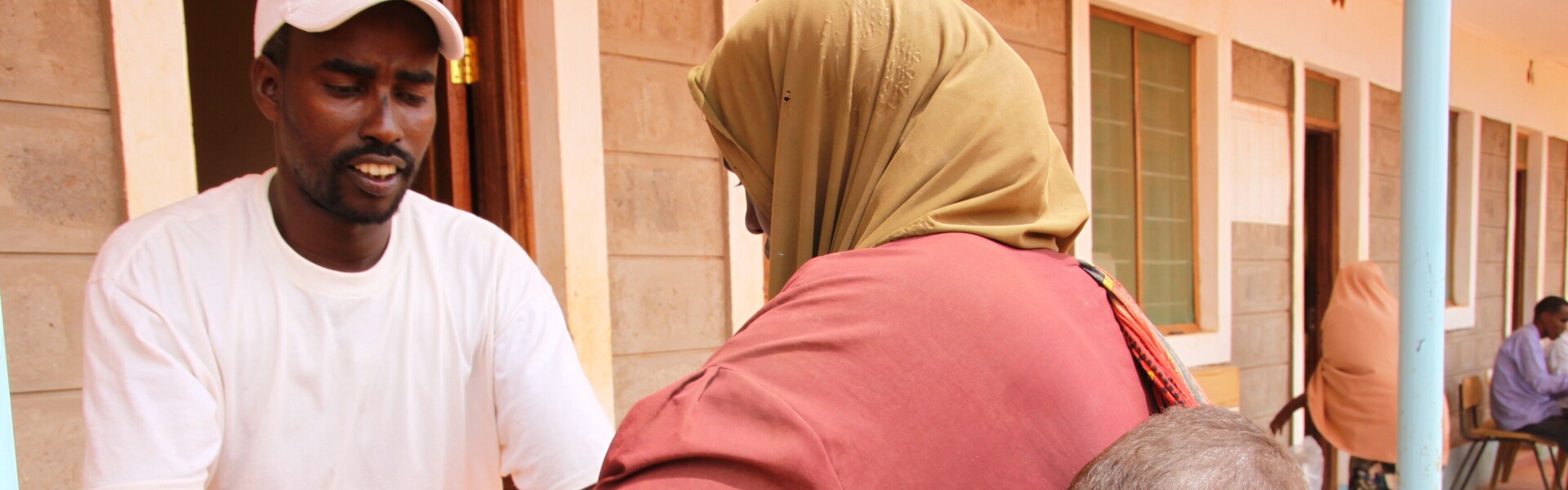 Helfer gibt Frau und Kind eine Tüte im FLüchtlingslager in Dadaab