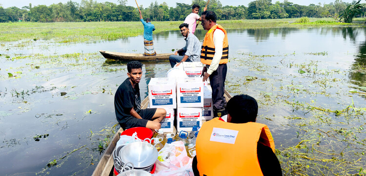 Nach Überschwemmungen in Bangladesch bringen Helfer in einem Boot Essen und Trinkwasser zu den Betroffenen Nach Überschwemmungen in Bangladesch bringen Helfer in einem Boot Essen und Trinkwasser zu den Betroffenen