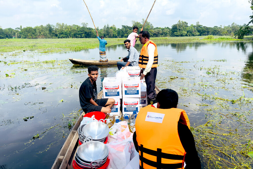 Nach Überschwemmungen in Bangladesch bringen Helfer in einem Boot Essen und Trinkwasser zu den Betroffenen Nach Überschwemmungen in Bangladesch bringen Helfer in einem Boot Essen und Trinkwasser zu den Betroffenen