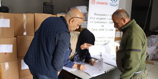 Drei Helfende bei der Verteilung von Hilfsgütern