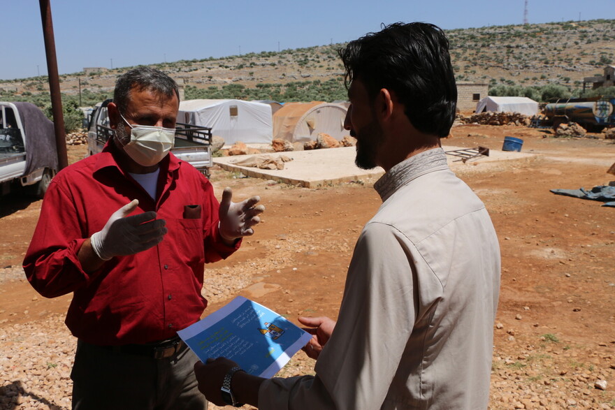Ein Helfer klärt in einem Flüchtlingscamp in Syrien über Corona auf Ein Helfer klärt in einem Flüchtlingscamp in Syrien über Corona auf