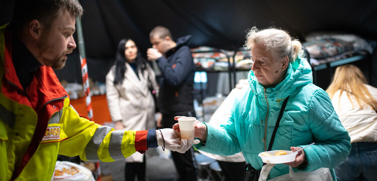 Eine Helferin verteilt warme Getränke in der Ukraine
