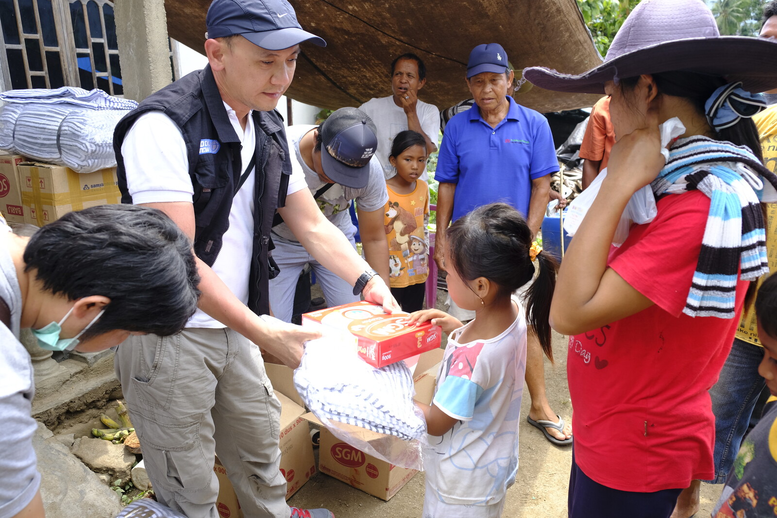 Helfer verteilen an Kinder, Frauen und Männer auf Sulawesi Nahrungsmittel